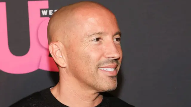 Jason Oppenheim wearing a black jumper smiling on red carpet in LA