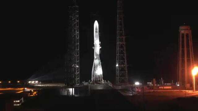 The Blue Origin rocket lit up with lights against a black sky