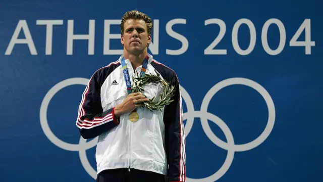 Gary Hall Jr. of the United States stands on the medal stand during the national anthem after receiving his medal for the men's swimming 50 metre freestyle event on August 20, 2004 during the Athens 2004 Summer Olympic Games at the Main Pool of the Olympic Sports Complex Aquatic Centre in Athens, Greece