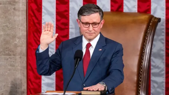 Mike Johnson is sworn in after being elected Speaker of the House, wearing a red tie and a navy suit