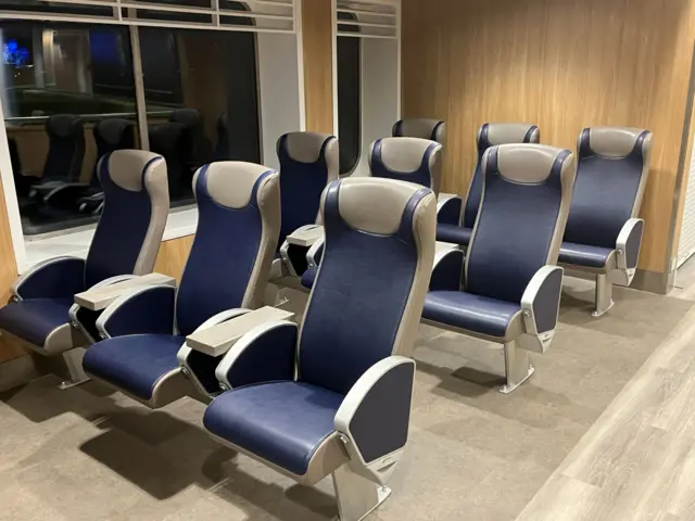 Navy blue and grey airline style seating in three rows of three next to large floor to ceiling windows