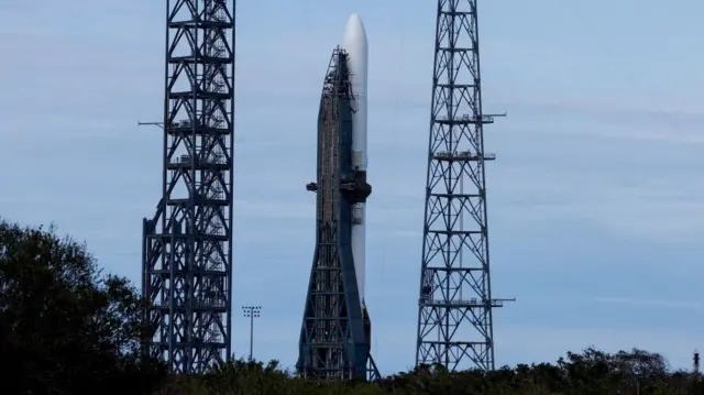 The New Glenn rocket stands against a blue sky