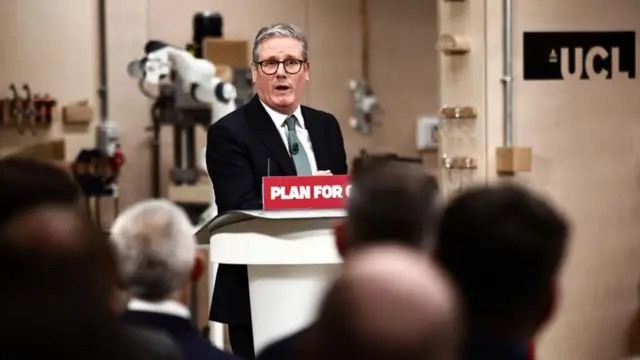 Keir Starmer, wearing a black suit and blue tie, speaking at a lectern that reads: "plan for change".