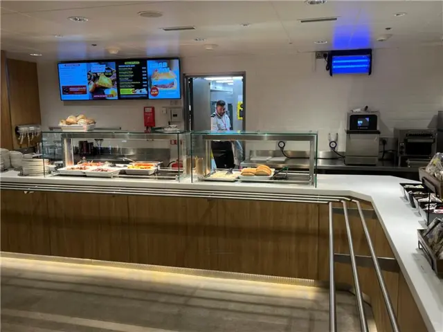 View of catering area - a chef working and some breakfast foods visible on a hot plate