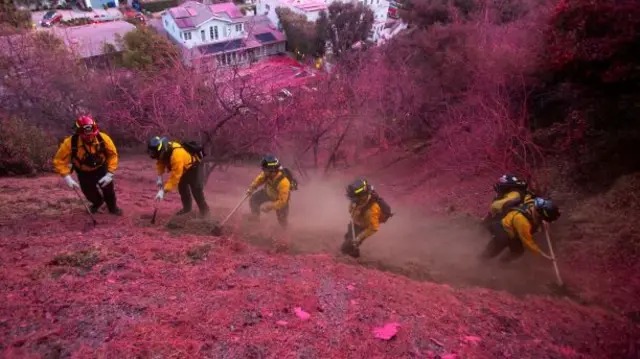 Firefighters work to clear a firebreak as the Palisades Fire