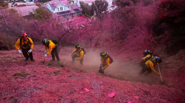 Firefighters clear a firebreak