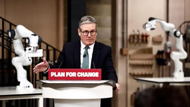 Keir Starmer, wearing a black suit and blue tie, speaking at a lectern that reads: "plan for change".