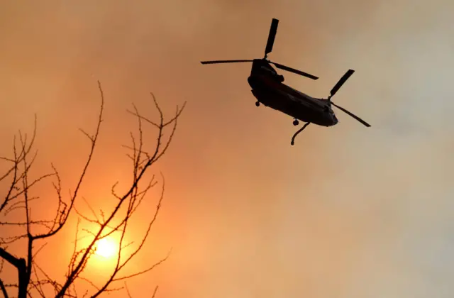 A chopper tackles the Palisades fire on Monday