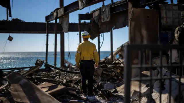 Firefighter inspects a property destroyed by fire in Palisades Fire