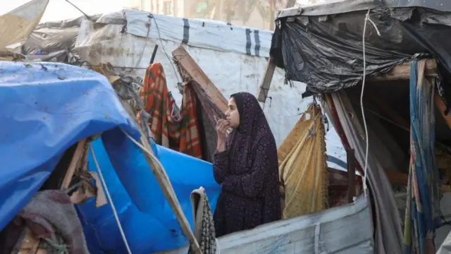 A Palestinian woman looks on at the site of an Israeli strike on a tent camp for displaced people, amid the ongoing conflict between Israel and Hamas, in Deir Al-Balah in the central Gaza Strip, January 14, 2025.