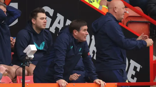 Mansfield manager Nigel Clough rests his hands on the advertising hoardings