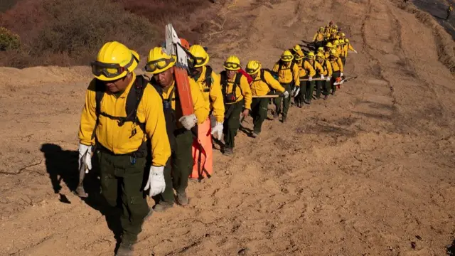 Firefighters from Mexico hike to their destination to cut a containment line in the Tarzana area during the Palisades Fire in Los Angeles,