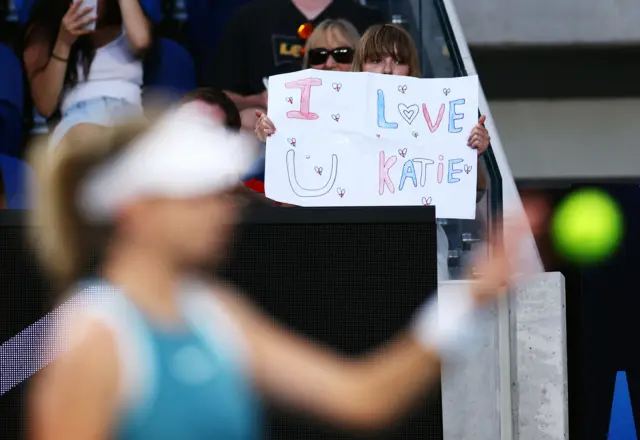 A girl holding a sign saying 'I love u Katie'