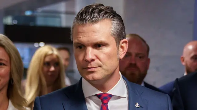 A file photo of Hegseth. He is wearing a suit and arriving at an event surrounded by others