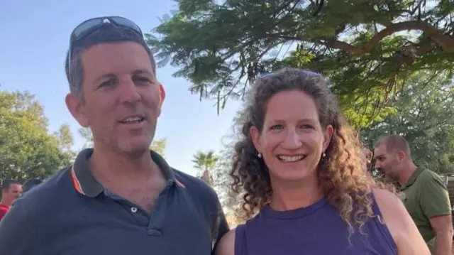 A picture of a smiling couple outside on a sunny day wearing tshirts