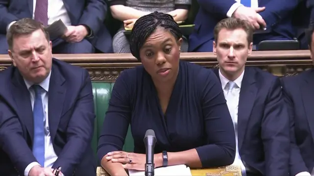 Kemi Badenoch stands and speaks into a microphone in the House of Commons