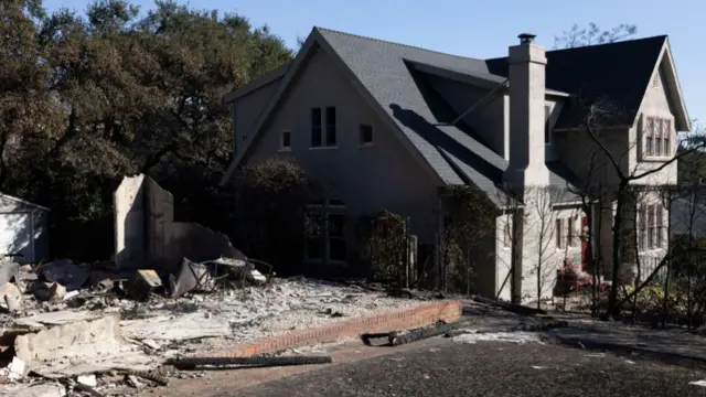 Aftermath of Eaton fire shows a grey two-storey house in California stays standing while the house next door has been levelled.