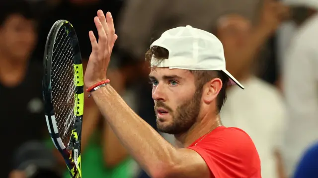 Jacob Fearnley claps his racquet to the crowd after beating Nick Kyrgios