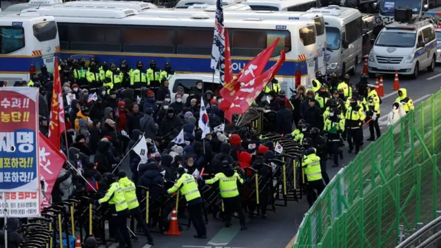 Yoon supporters push over a barricade set up by the police