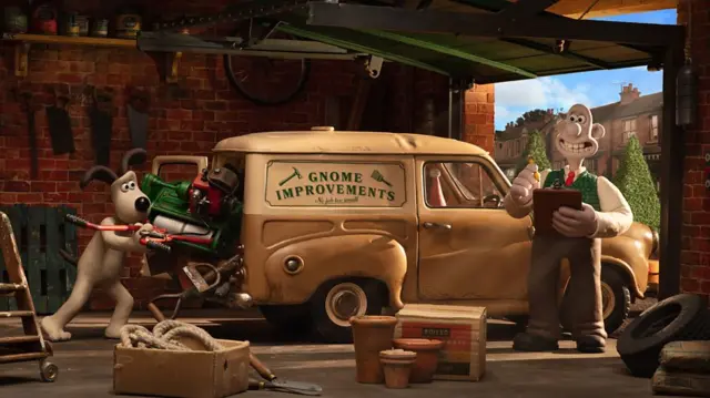 Scene from Wallace and Gromit: Vengeance Most Fowl. Wallace and Gromit in a garage beside a van with "Gnome Improvements" written on the side. Gromit struggles to fit lots of equipment into the back of the van, while Wallace smiles and holds a clipboard.