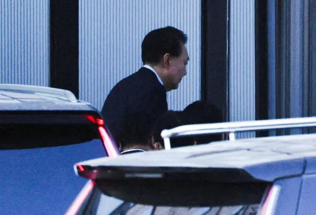 Yoon Suk Yeol photographed from behing as he exits a black vehicle