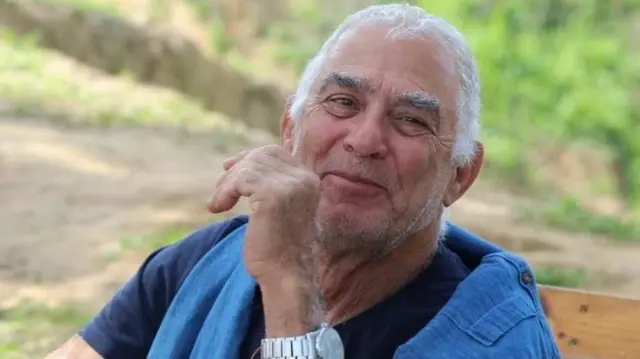 Gadi Moses, an 80-year-old man, is seen smiling outside on a sunny day