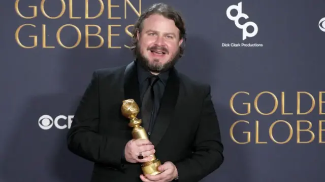 Brady Corbet holds a Golden Globe