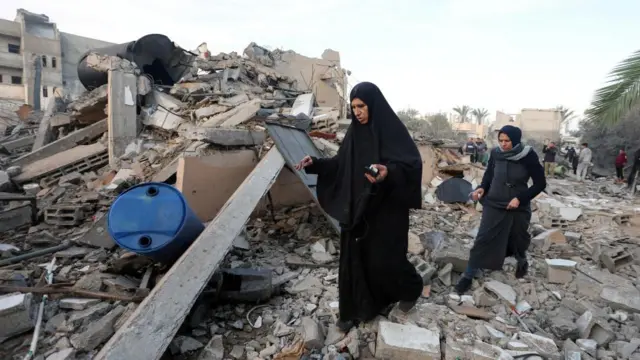 Palestinians inspect the site of an Israeli strike on a house