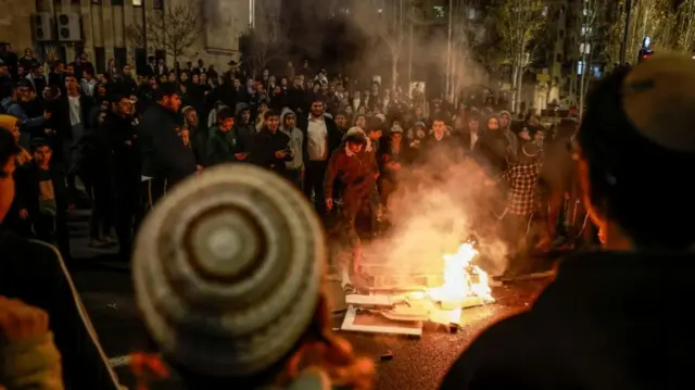 Protestors gather around a fire burning placards