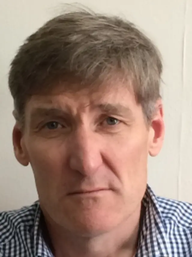 Rob Thomas, who is clean shaven and has light brown/grey hair with a fringe. He has blue eyes and is looking directly down the camera