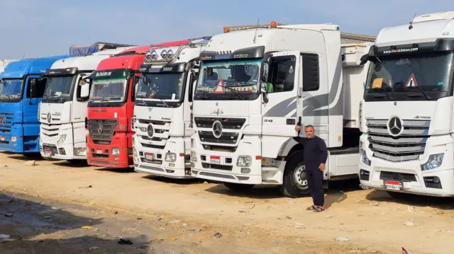 A driver stands next to trucks carrying aid lined up near the Rafah border, waiting to cross into the Gaza Strip, following the announcement of a ceasefire agreement between Israel and Hamas, in Al Arish, Egypt, January 16, 2025.