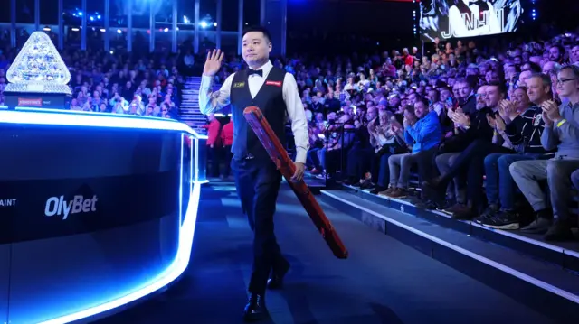 Ding Junhui walks into the arena at the Masters