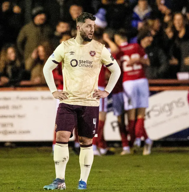 Hearts' Craig Halkett looks dejected as Brechin's Scott Bright celebrates with his teammates as he scores to make it 1-0 during a Scottish Gas Men's Scottish Cup Fourth Round match between Brechin City and Heart of Midlothian at Glebe Park, on January 17, 2025, in Brechin, Scotland. (Photo by Paul Devlin / SNS Group)