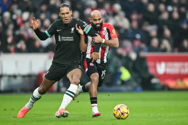 Virgil van Dijk (L) fights for the ball with Brentford's French-born Cameroonian striker #19 Bryan Mbeumo.