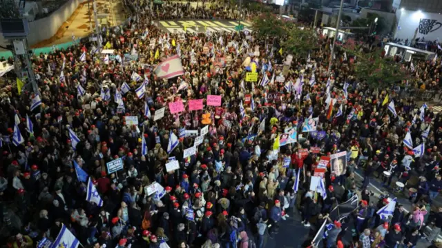 People hold placards and wave flags during an anti-government protest calling for action to secure the release of Israeli hostages