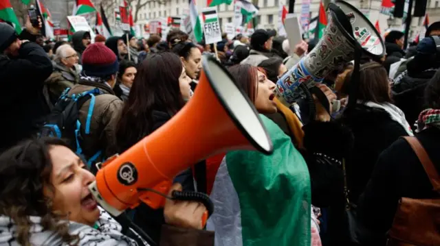 Pro-Palestinian activists with megaphones draped in the Palestinian flag