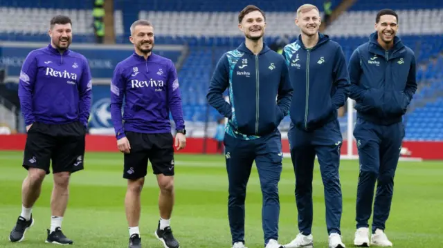 Swansea players walk the pitch at the Cardiff City Stadium