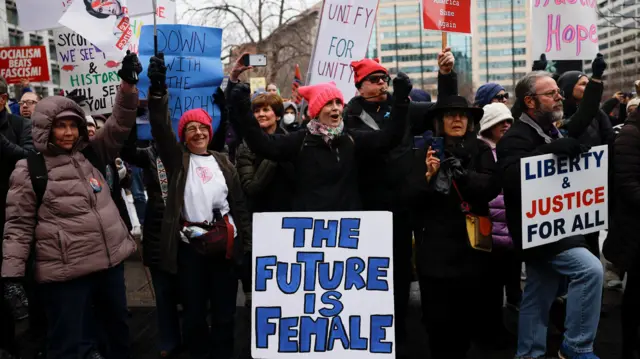 People protesting, with signs, including one which says 'The future is female'