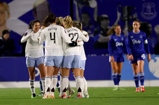 Villa players celebrate as Everton players trudge back to kick off