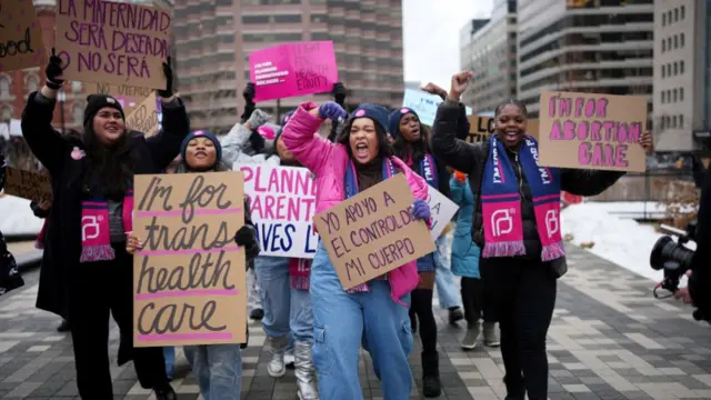 A group of women march, holding placards