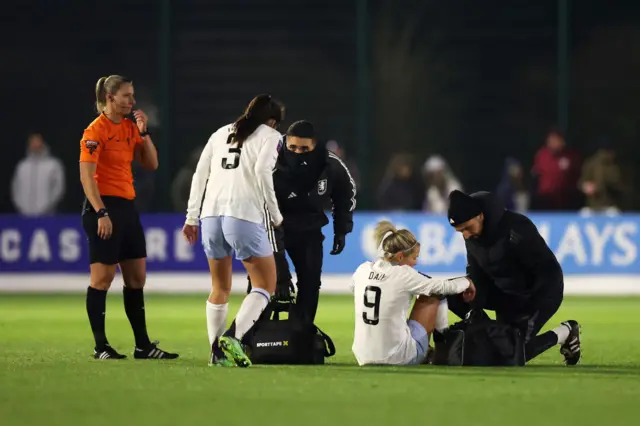 Daly is tended to on the pitch by the Villa physios