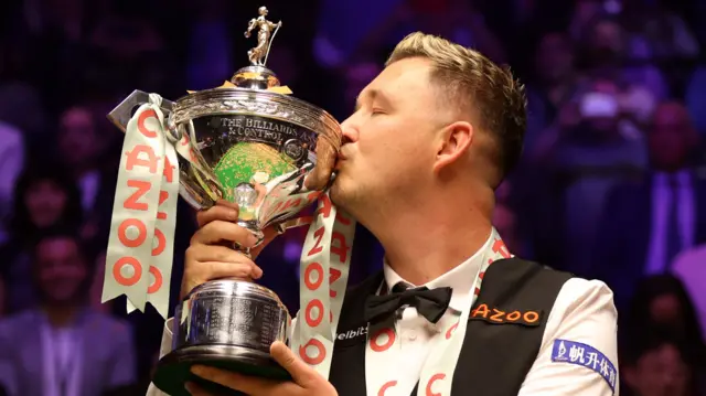 Kyren Wilson kisses the World Championship trophy