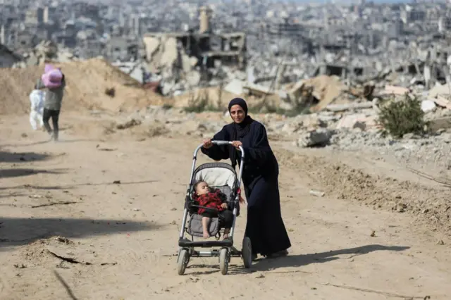 A Palestinian woman pushes a child in Jabalia earlier today, hours after the ceasefire began