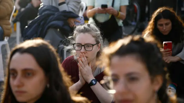 In Tel Aviv, people gather in a square to watch broadcasts related to the expected release of the three women