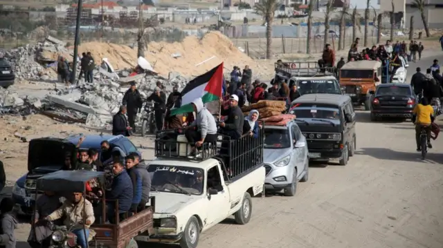 Internally displaced Palestinians make their way past rubble