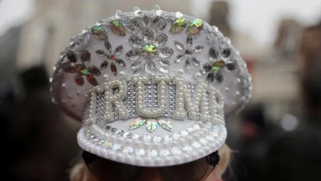 A woman wearing a white hat with "Trump" written on it