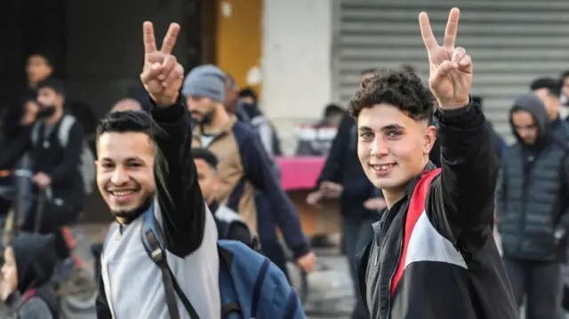 Two young men in Gaza city smiling at the camera and gesturing the peace sign on Sunday morning 19 Jan