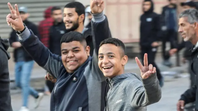 Two young people smiling to camera and gesturing the peace sign in Gaza city on Sunday morning 19 Jan