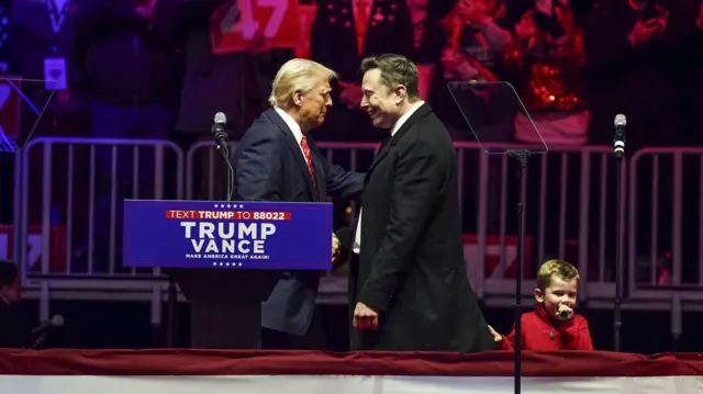 Trump and Musk shake hands on stage