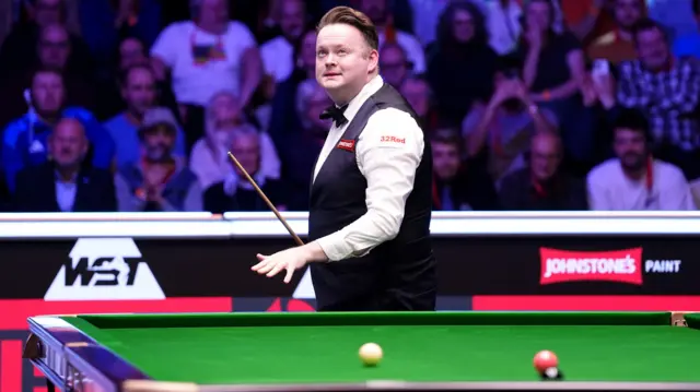 Shaun Murphy walks around the table